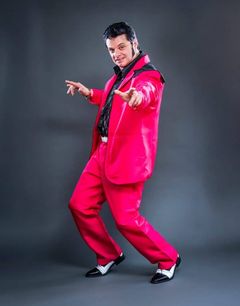 Rocking Elvis tribute artist performing in a pink suit