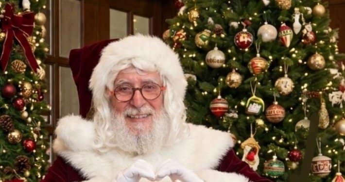 Santa Serge, professional Santa with a natural beard, making a heart with his hands