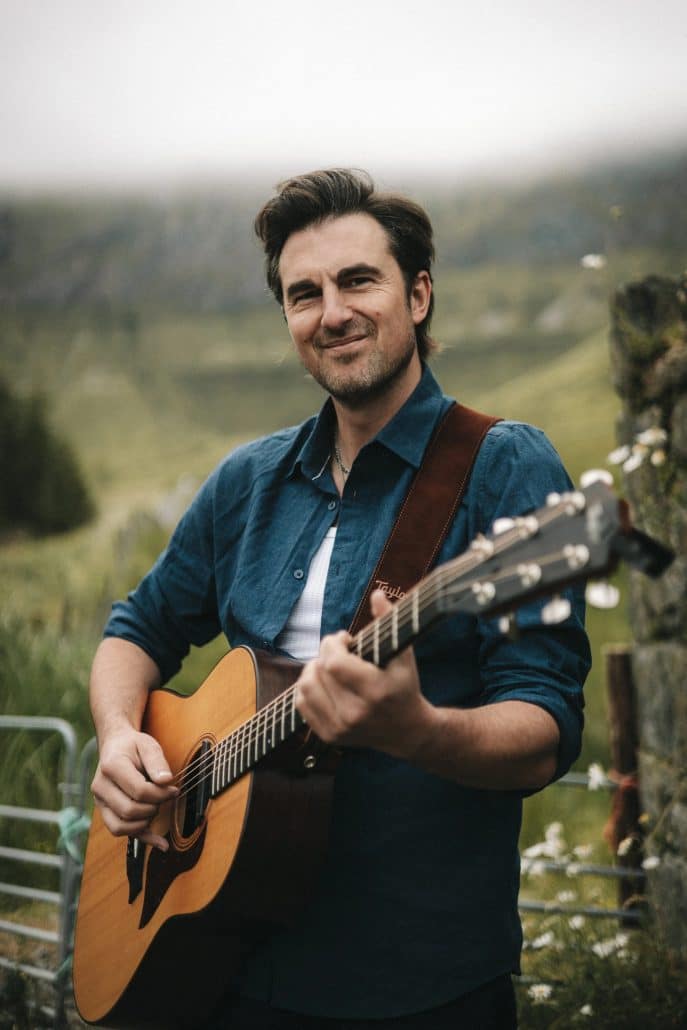 Tommy Novak with acoustic guitar outdoors